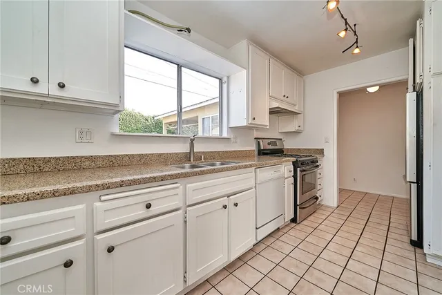a kitchen with granite countertop white cabinets white appliances a sink and a window