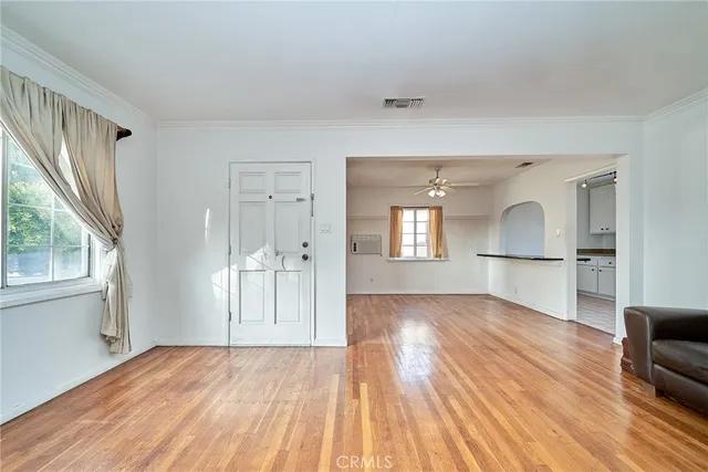 a view of empty room with wooden floor and fan