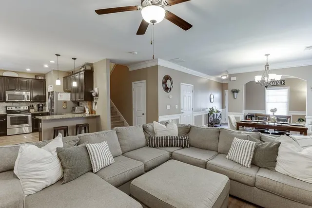 a living room with furniture kitchen view and a chandelier