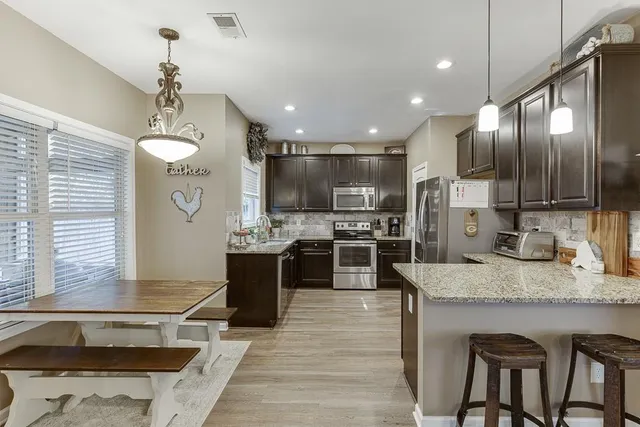 a large kitchen with granite countertop lots of counter top space and stainless steel appliances