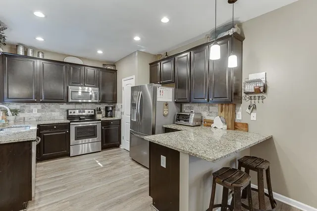a kitchen with kitchen island granite countertop stainless steel appliances and wooden cabinets