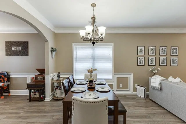 a view of a dining room and livingroom with furniture wooden floor a chandelier