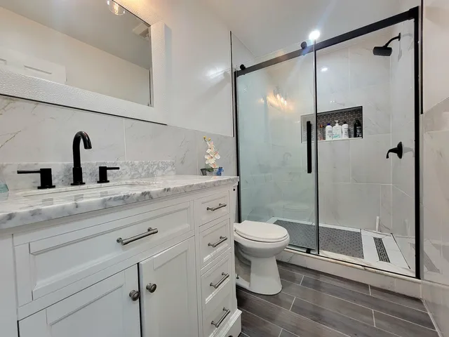 a bathroom with a sink a toilet and shower