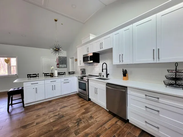 a kitchen with cabinets stainless steel appliances and wooden floor