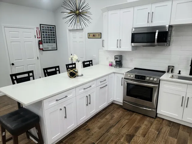 a kitchen with stainless steel appliances a table chairs microwave and cabinets