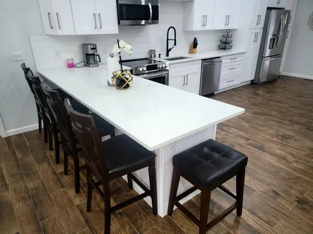 a living room with stainless steel appliances kitchen island granite countertop furniture and a wooden floor