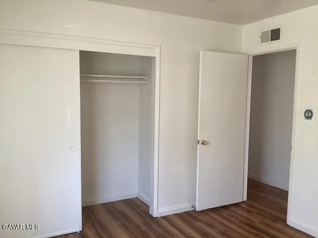 a view of an empty room with wooden floor and closet