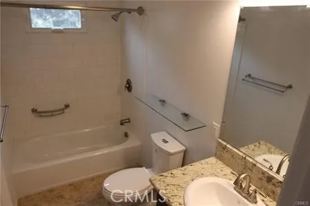 a bathroom with a granite countertop toilet and a bathtub