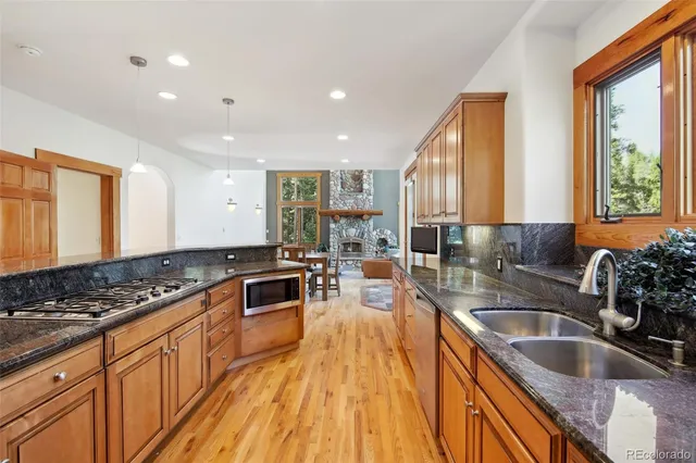 a kitchen with stainless steel appliances granite countertop a sink stove and wooden cabinets