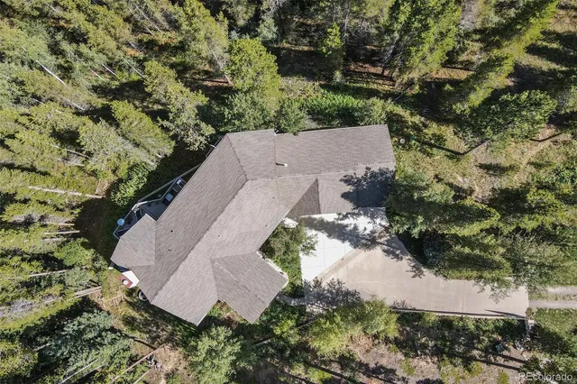 an aerial view of a house with a yard and trees all around