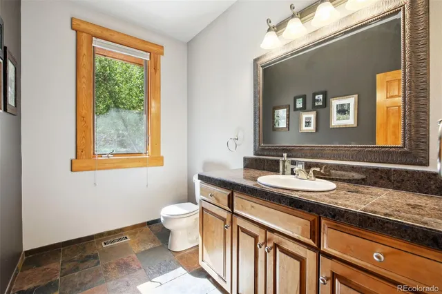 a bathroom with a granite countertop toilet sink and mirror