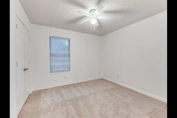 an empty room with a window and a fan