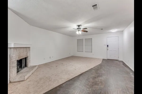 an empty room with chandelier fan and fire place