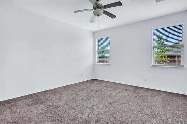 a view of an empty room with wooden floor and a ceiling fan