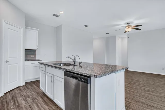 a kitchen with stainless steel appliances granite countertop a sink and dishwasher with wooden floor