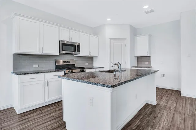 a kitchen with granite countertop a sink and a stove top oven