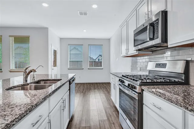 a kitchen with granite countertop a sink a stove and cabinets