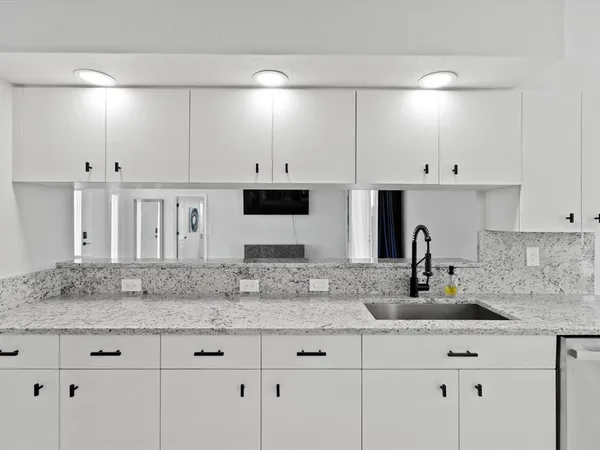 a kitchen with stainless steel appliances granite countertop a sink and white cabinets