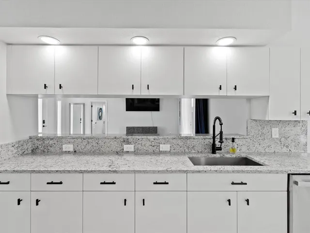 a kitchen with stainless steel appliances granite countertop a sink and white cabinets