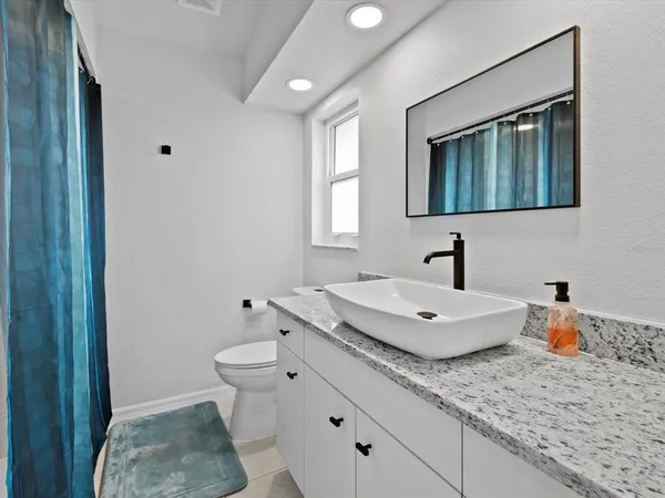 a bathroom with a granite countertop sink a toilet a mirror and shower