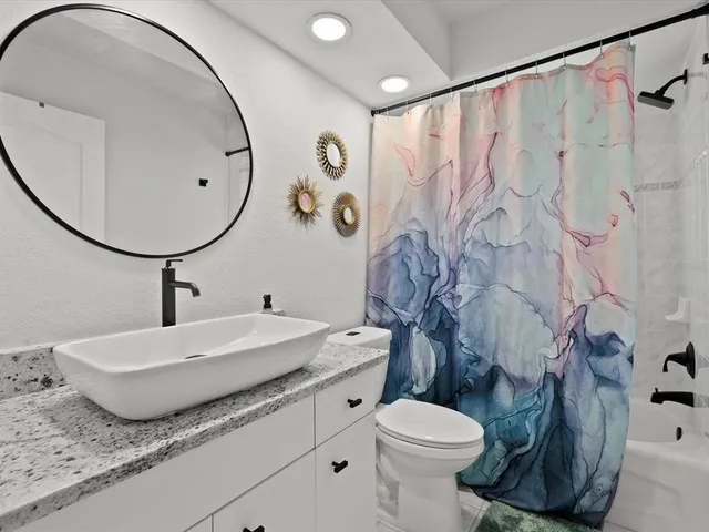 a bathroom with a granite countertop toilet sink and mirror