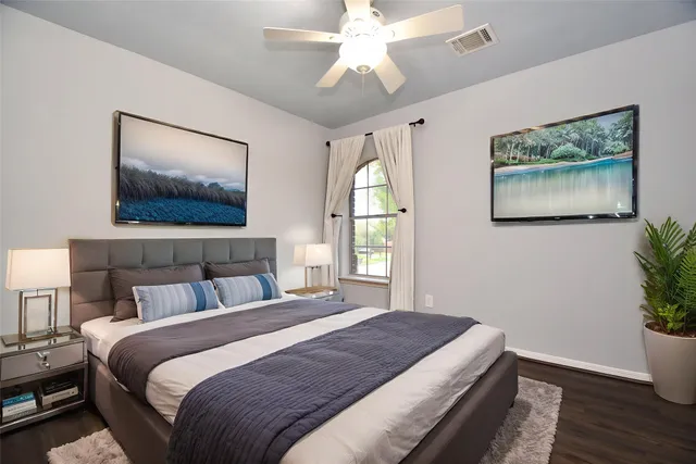 an empty room with wooden floor chandelier fan and windows