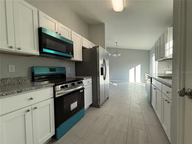 a kitchen with stainless steel appliances granite countertop a stove a refrigerator and a microwave