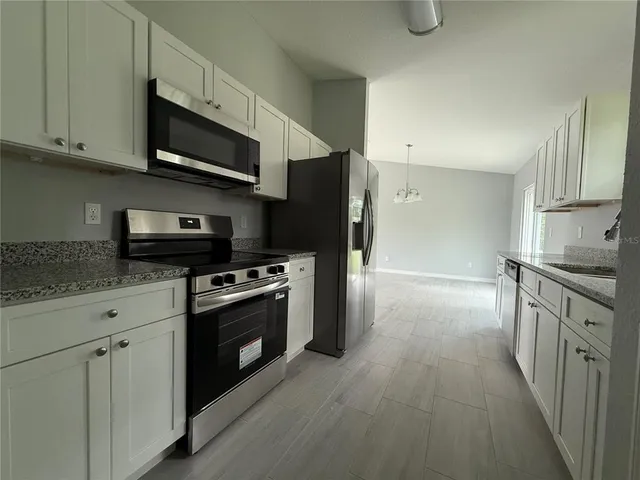 a kitchen with stainless steel appliances granite countertop a stove a sink and a refrigerator