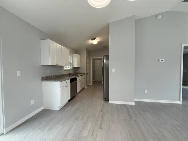 a kitchen with granite countertop a refrigerator and a stove top oven