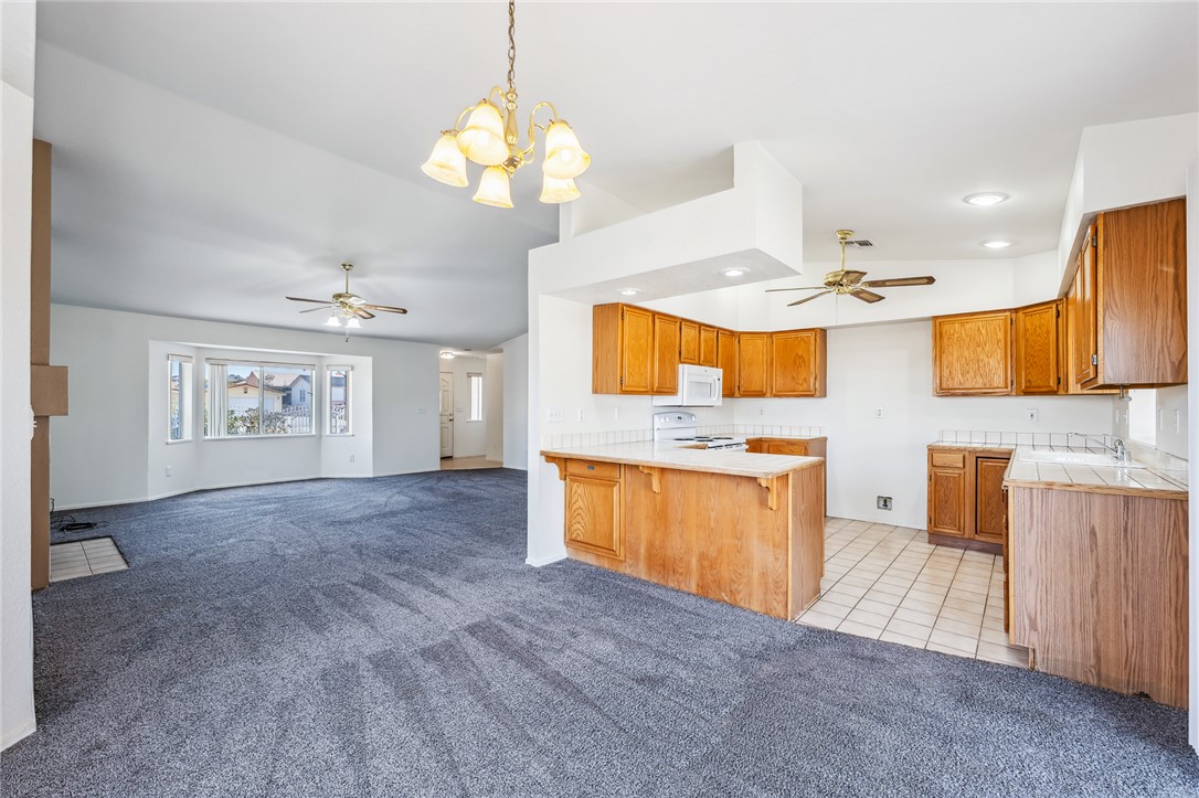 2524 South Ridge Avenue Bullhead City, AZ 86429 - Photo 18 of 64 Kitchen featuring ceiling fan, a peninsula, range, white microwave, and recessed lighting