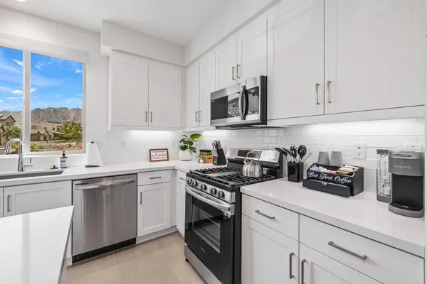a utility room with stainless steel appliances white cabinets and a sink