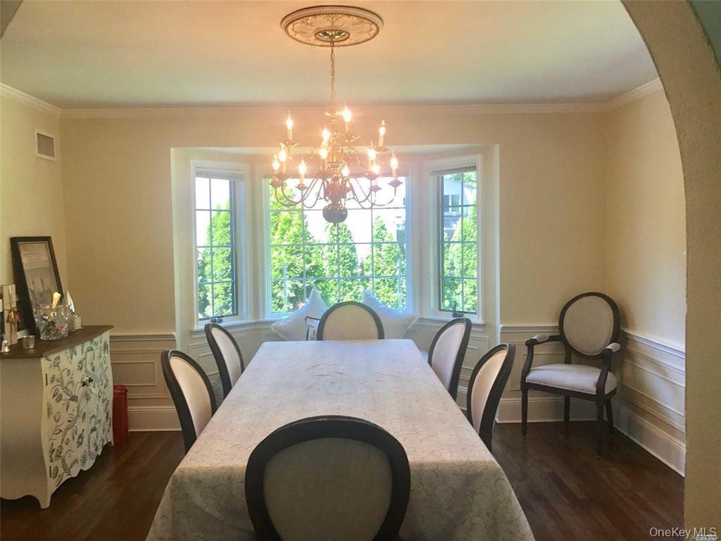 5 Rockcrest Road Manhasset, NY 11030 - Photo 9 of 16 Dining room with arched walkways, a chandelier, plenty of natural light, crown molding, and dark wood-style flooring