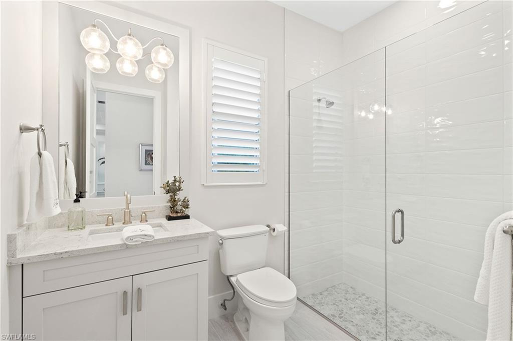 8829 Paradera Court Naples, FL 34112 - Photo 15 of 31 a bathroom with a toilet a sink a mirror a vanity and window