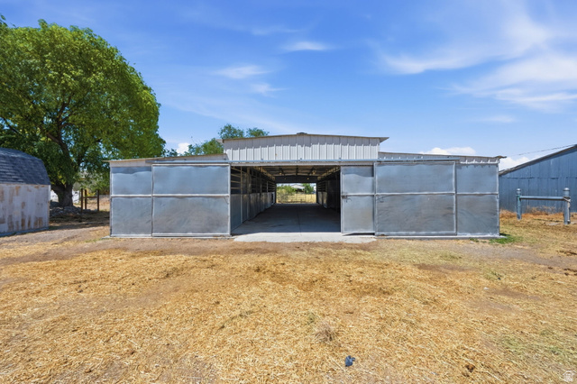 3732 Campbell Road Tooele, UT 84074 - Photo 4 of 69 Open-air metal barn structure with multiple stalls, a wide central aisle, and a metal roof