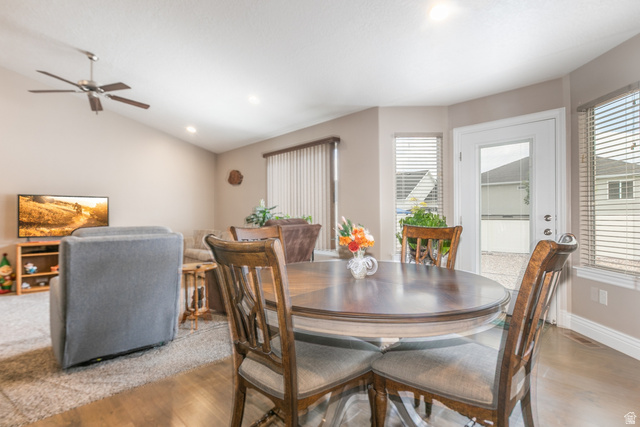 1228 North Providence Way Tooele, UT 84074 - Photo 7 of 28 Bright dining area featuring a round wood-finish table and chairs, wood-finish flooring, a glass-paned exterior door, and multiple windows with blinds