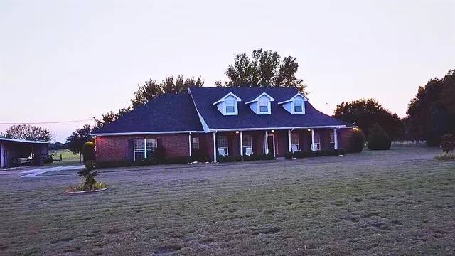 a view of a big house with a big yard and large trees