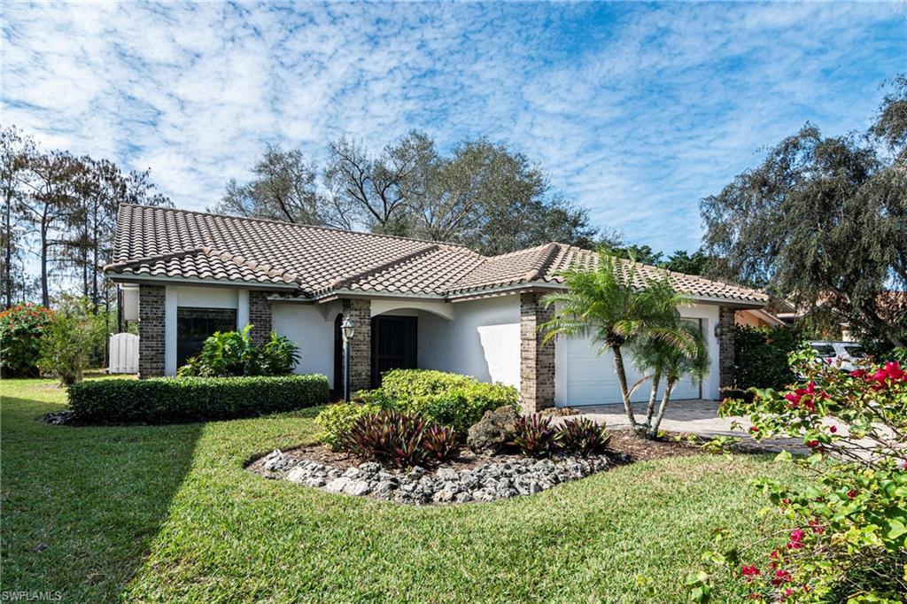 249 St James Way Naples, FL 34104 - Photo 2 of 23 a front view of a house with a garden