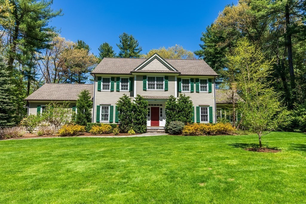 a front view of a house with garden and trees