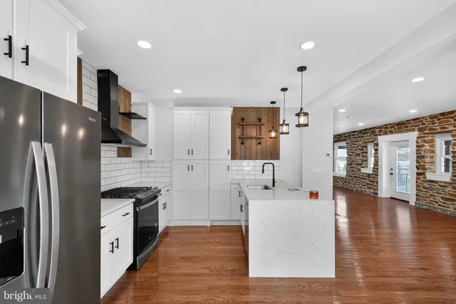 a large kitchen with stainless steel appliances kitchen island granite countertop a refrigerator and a stove top oven