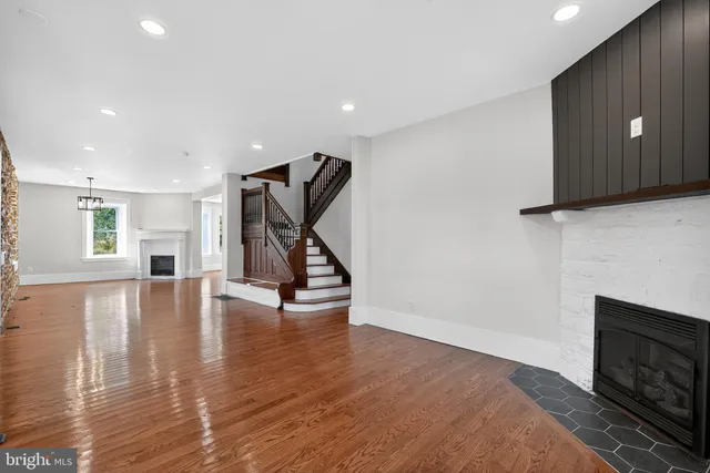 a view of an empty room with wooden floor and a fireplace