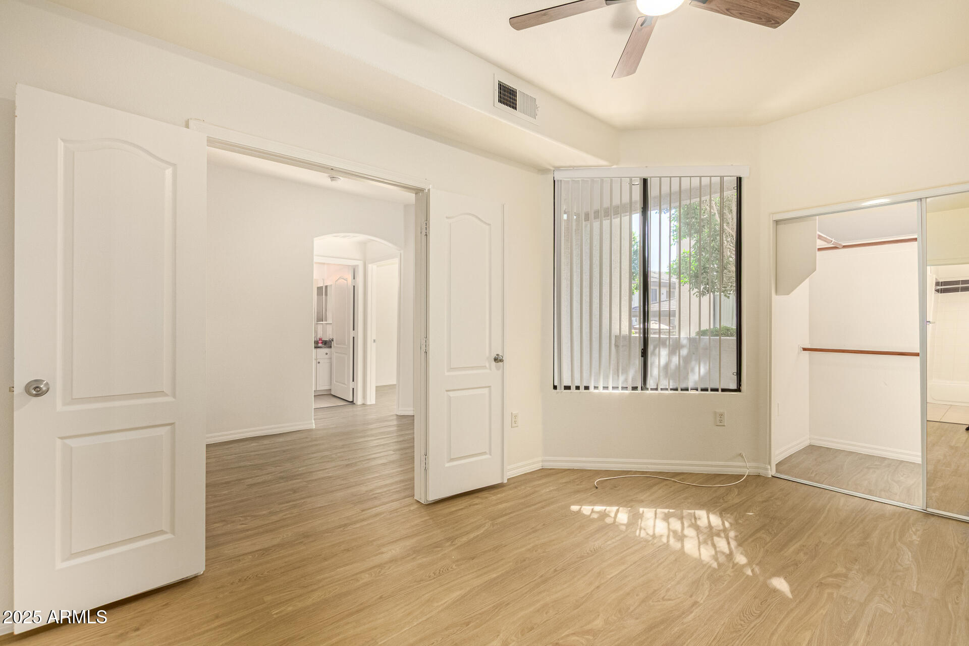 a view of an empty room with wooden floor and a window