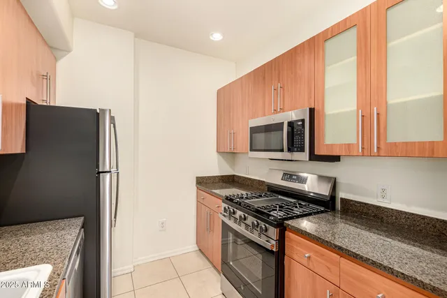 a kitchen with stainless steel appliances granite countertop a stove a refrigerator and a microwave
