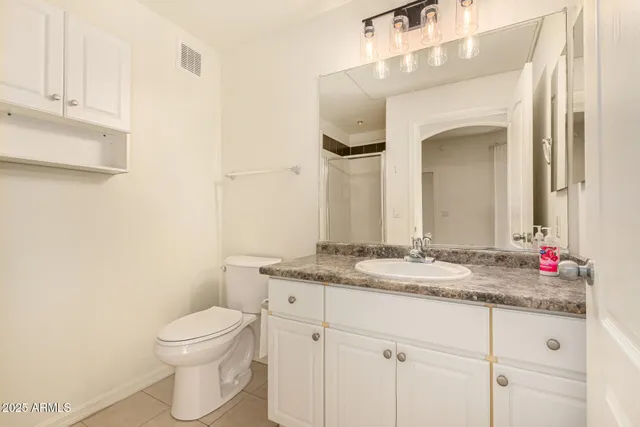 a bathroom with a granite countertop sink vanity mirror and toilet