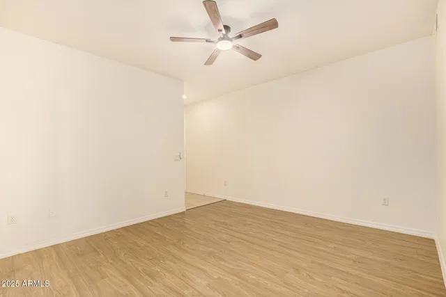an empty room with wooden floor and a ceiling fan