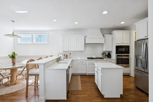 a kitchen with a refrigerator a stove and white cabinets with wooden floor