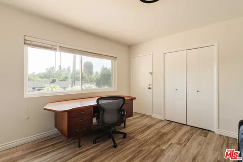 a view of a workspace with wooden floor and a window