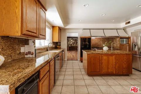 a kitchen with granite countertop a sink a counter top space cabinets and stainless steel appliances