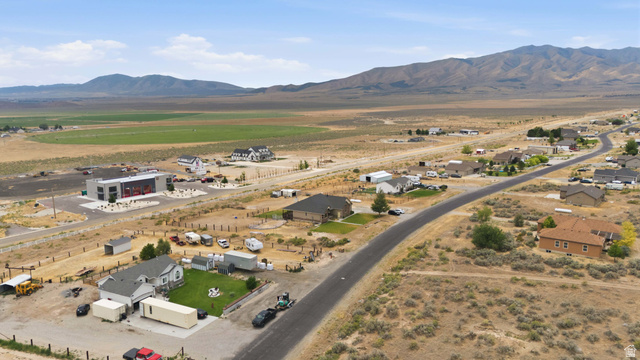 2567 West Rim Rock Drive Stockton, UT 84071 - Photo 59 of 64 Aerial perspective showcasing a residential street with diverse home styles, set against a backdrop of mountains and expansive open land