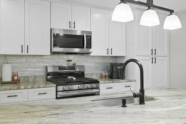 a kitchen with stainless steel appliances kitchen island granite countertop a stove a sink and a microwave