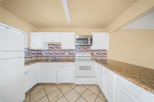 a kitchen with granite countertop white cabinets and white appliances